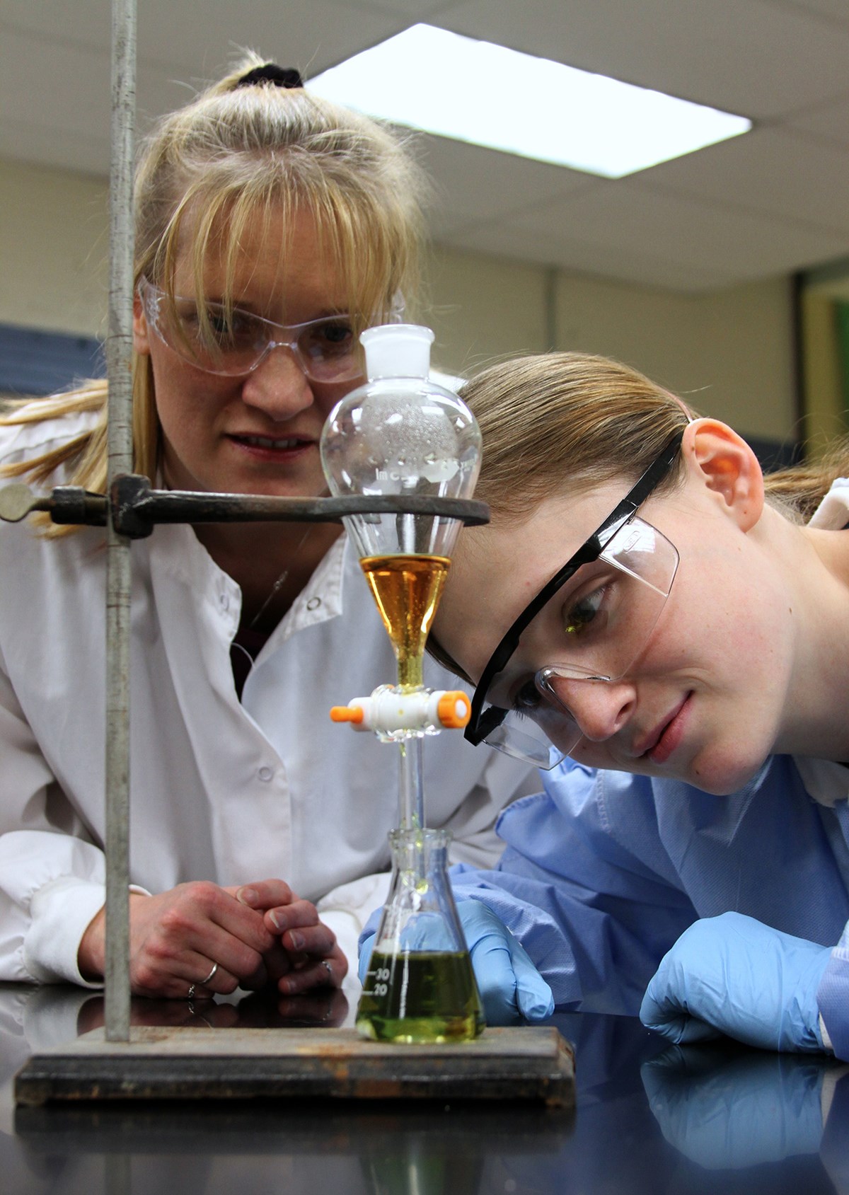 A Chemistry faculty member and student watch closely as a liquid is heated in a lab experiment.